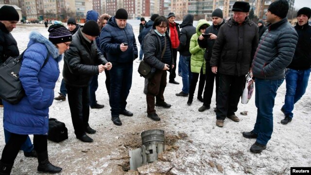 People look at the remains of a rocket that hit a residential  street in the eastern town of Kramatorsk on February 10.