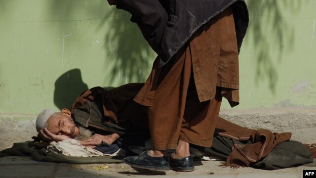 An elderly man lies on the ground as he begs in Kandahar. (file photo)