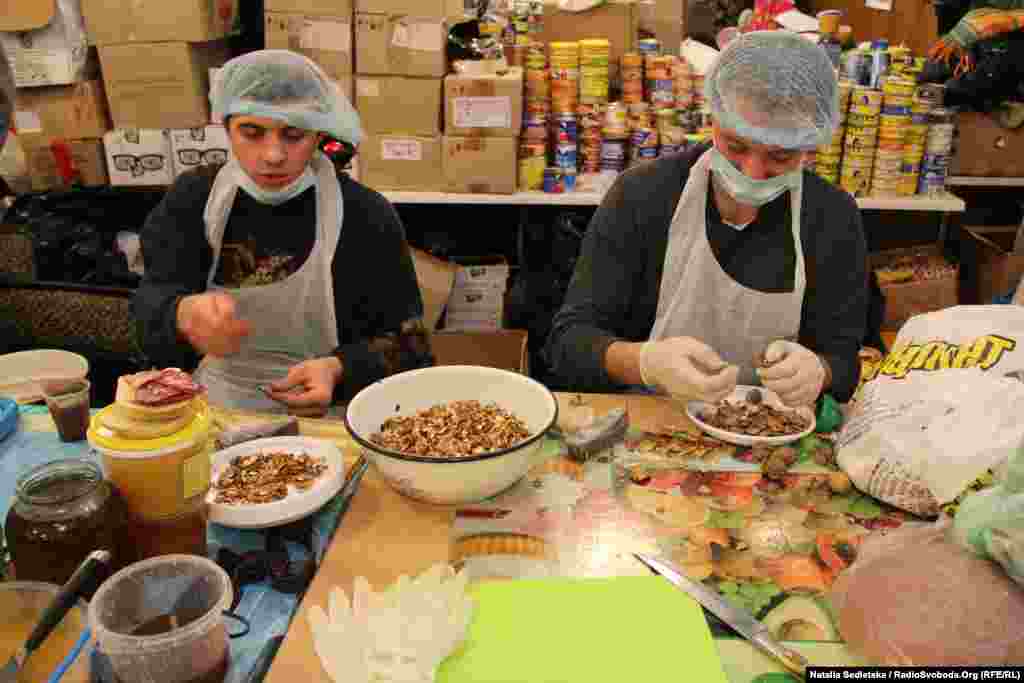 Volunteers in gloves and hairnets prepare food at the dining hall of a trade union building, the main kitchen offering food to the protesters.