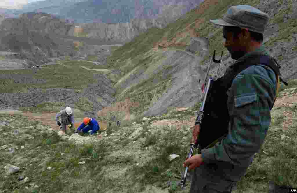 An Afghan policeman stands guard over mining operations.