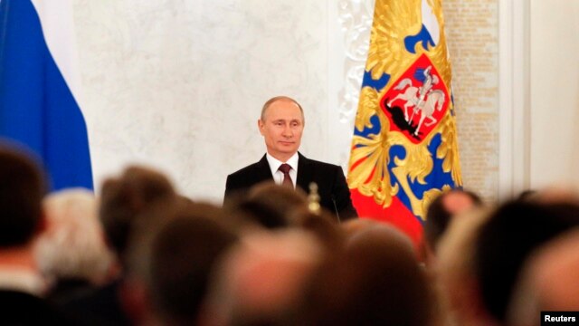 Russian President Vladimir Putin on March 18, 2014, addresses the Federal Assembly, including State Duma deputies, members of the Federation Council, regional governors, and civil society representatives on the annexation of Ukraine's Crimea region.