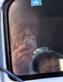 A Chechen refugee holds a stack of dollars as he and his grandson approach a republican checkpoint (file photo) (AFP)