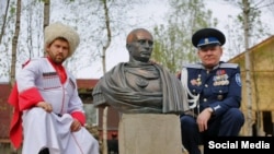Cossacks pose next to a bust of Vladimir Putin in the guise of a ROman emperor.