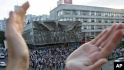 A protester applauds as people gather during a demonstration in Minsk organized via social networks.