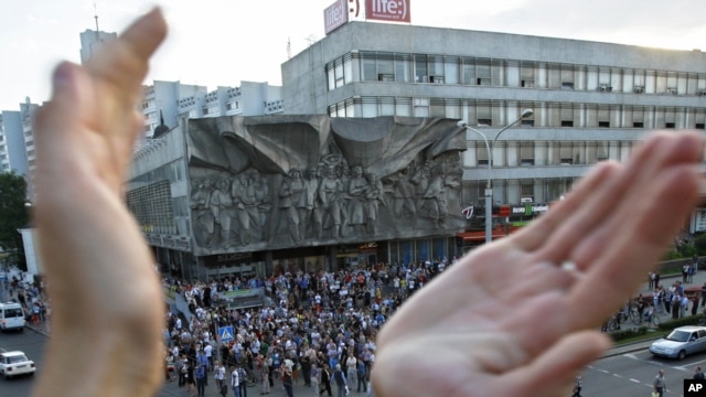 A protester applauds as people gather during a demonstration in Minsk organized via social networks. 