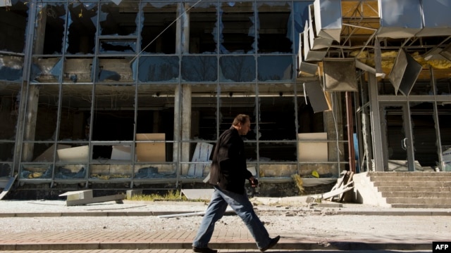 A man walks past a building damaged in recent shelling in Donetsk's Kyivskiy district, near the airport,  on October 7.