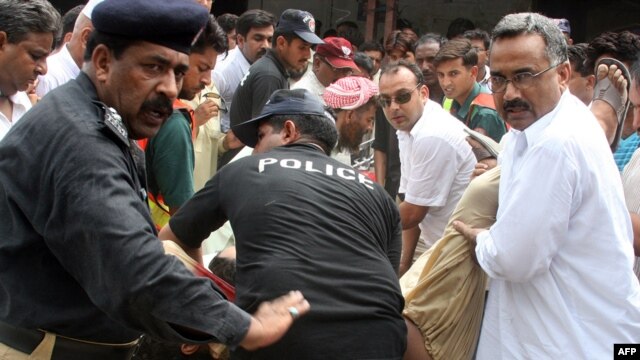 Pakistani security officials carry the bodies of two Christians killed outside a court in Faisalabad on July 19.