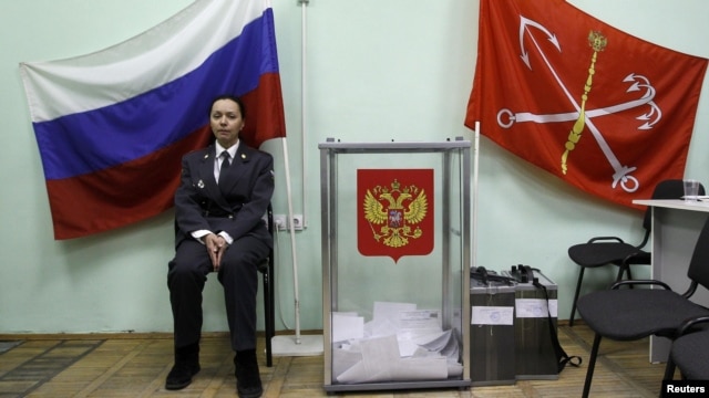 A police officer sits next to a ballot box at a polling station in St. Petersburg on March 4. The OSCE says the vote count was faulty in almost one-third of the polling stations observed.
