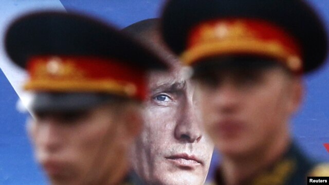 Navy sailors walk past an election billboard for Putin's party in St. Petersburg in September 2011