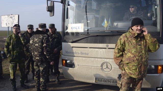 OSCE military observers talk on the phone as they wait at the Chongar checkpoint blocking the entrance to Crimea on March 7.