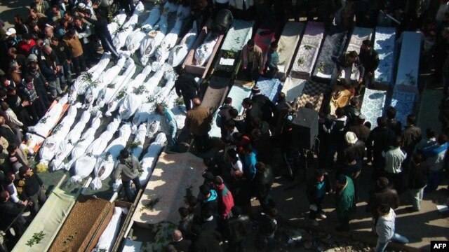 A handout picture obtained from Syrian opposition activists in Homs shows mourners gathered around coffins and bodies during a mass funeral in the city of Homs on February 4.