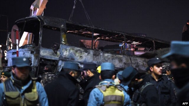 Afghan policemen stand next to the burned out wreckage of an army bus at the scene of a deadly suicide attack in Kabul on December 13.