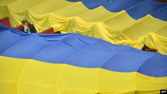 A deputy sits next to huge Ukrainian flags decorating the benches of opposition deputies who left a parliamentary session in June to protest a language bill.