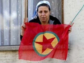 A Kurdish woman waves a PKK flag from her house in Diyarbakir, Turkey. 