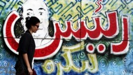سيدة مصرية تمر أمام ملصق في ميدان التحرير مكتوب علية (ريّس لبكرة)