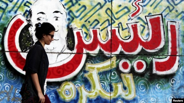 سيدة مصرية تمر أمام ملصق في ميدان التحرير مكتوب علية (ريّس لبكرة)