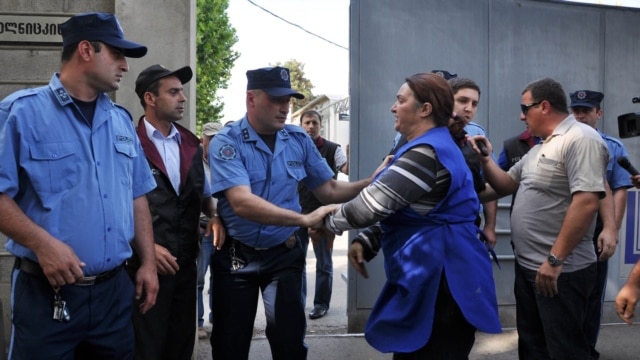 Georgian police grapple with workers as they seize dishes at a satellite TV outlet on June 1. 