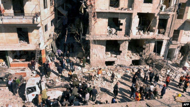 Syria -- Investigators inspecting the blast scene outside a damaged building following a car bomb in the northern city of Aleppo, 18Mar2012