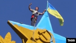 A Moscow city worker takes a selfie while atop the Kotelnicheskaya Embankment building in Moscow to remove the Ukrainian flag mounted there overnight on August 19-20. The hammer-and-sickled star and laurel wreath was also painted in Ukrainian colors.