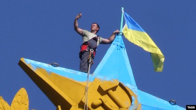 A Moscow city worker takes a selfie while atop the Kotelnicheskaya Embankment building in Moscow to remove the Ukrainian flag mounted there overnight on August 19-20.