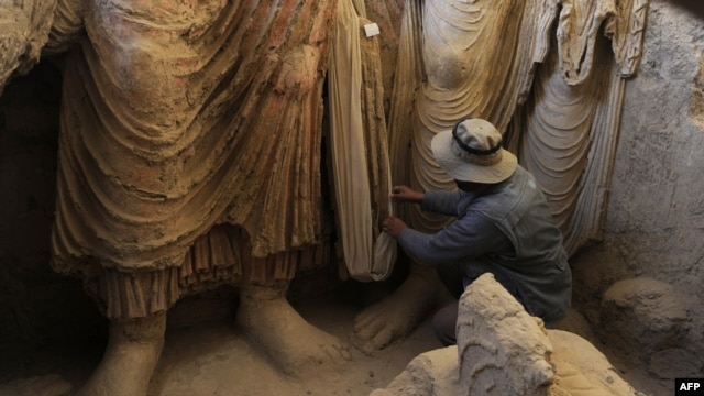 An archaeologist looks at the remains of Buddha statues discovered inside an ancient monastery in Mes Aynak in Afghanistan's eastern province of Logar.