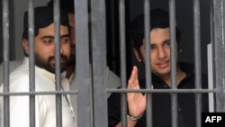 Shahrukh Jatoi (right) gestures while his accomplice Siraj Talpur looks on from a court lockup before being convicted for murder in the Pakistani port city of Karachi on June 7.