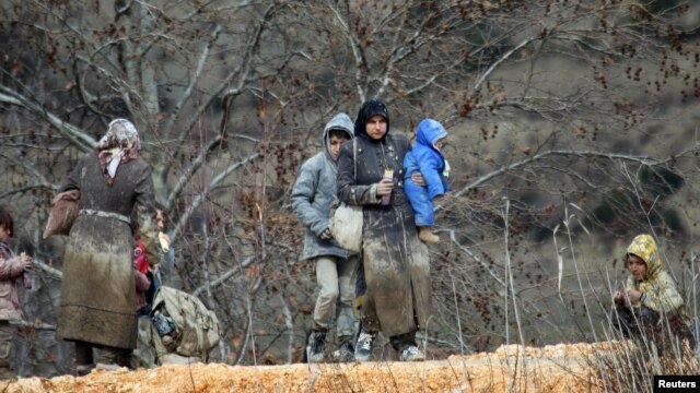 Internally displaced people, covered in mud, wait as they are stuck in the Syrian town of Khirbet al-Joz, in Latakia Province, waiting to get permission to cross into Turkey near the border on February 7.