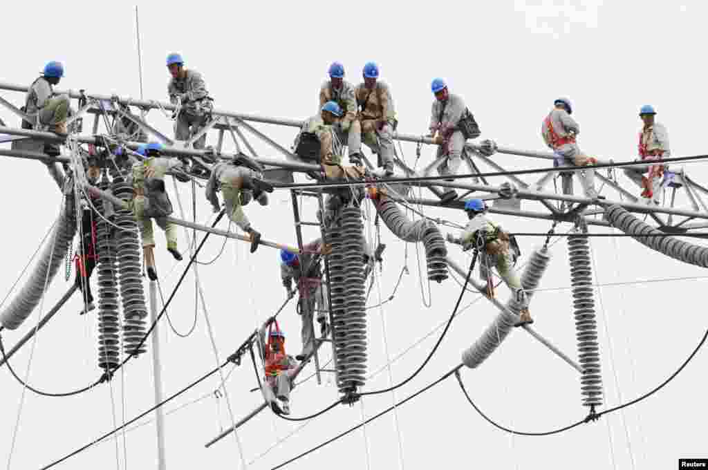 Chinese workers climb equipment to perform maintenance work at an electric-power-transformation substation in Xuzhou, in Jiangsu Province. (Reuters/China Daily)