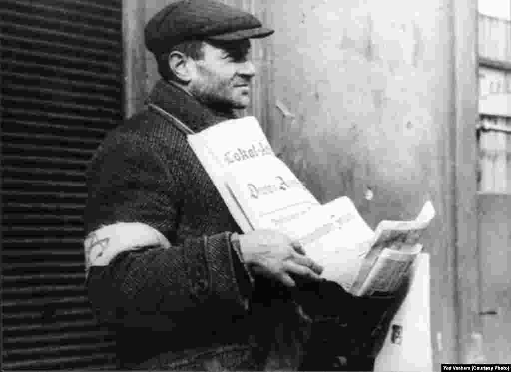 A Jew in the ghetto displays newspapers for sale.