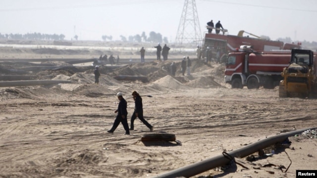 Employees of the Iraqi state-run South Oil Company (SOC) walk near a damaged pipeline in Al-Basrah province in December.