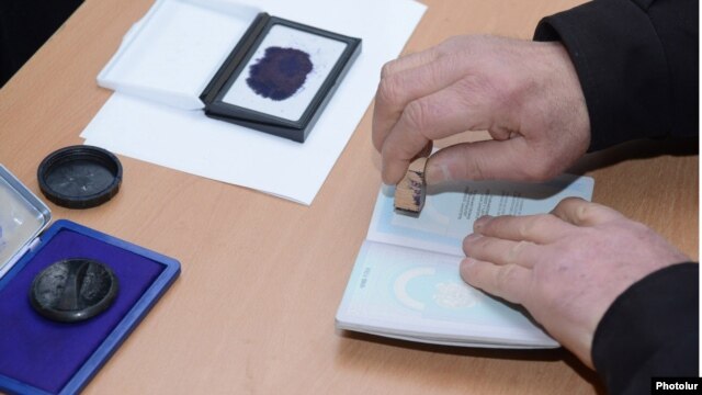 Armenia - An official at a polling station in Yerevan puts a special stamp on a voter's passport which is supposed to prevent multiple voting, 18Feb2013.