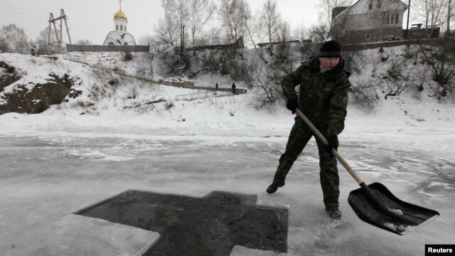 A worker prepares a cross-shaped bathing hole for Russian Orthodox Epiphany celebrations on the Mana River near the village of Ust-Mana on January 18.