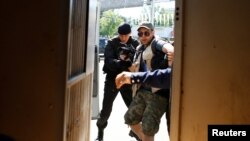 Полиция жер реформасына қарсылық акциясынан хабар таратпақ болған журналисті ұстап көлікке кіргізіп жатыр. Алматы, 21 мамыр 2016 жыл.