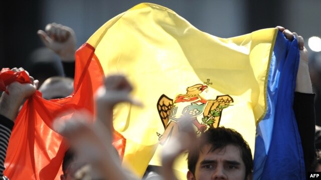 Protesters wave the Moldovan flag near the government building in Chisinau on April 8
