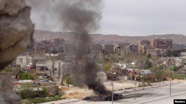 A tank belonging to government forces is set on fire during clashes between government forces and the Free Syrian Army, on the main southern highway near Damascus, on March 19.