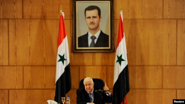 ولید المعلم، وزیر خارجه سوریه زیر عکسی از بشار اسد، رییس جمهوری این کشور.