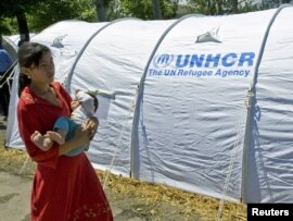 An ethnic Uzbek woman who fled from southern Kyrgyzstan walks with her child at a refugee camp in the village of Yorkishlak on the Kyrgyz-Uzbek border.