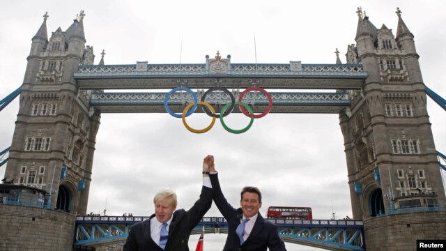 U.K. -- London Mayor Boris Johnson (L) and LOCOG Chairman Sebastian Coe pose for photos on a river boat under Tower Bridge after the the Olympic Rings were lowered into position for display in central London, 27Jun2012