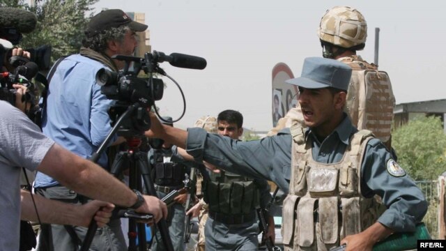 Afghan police keep journalists away from the site of a suicide car bomb attack in Kabul on August 18.