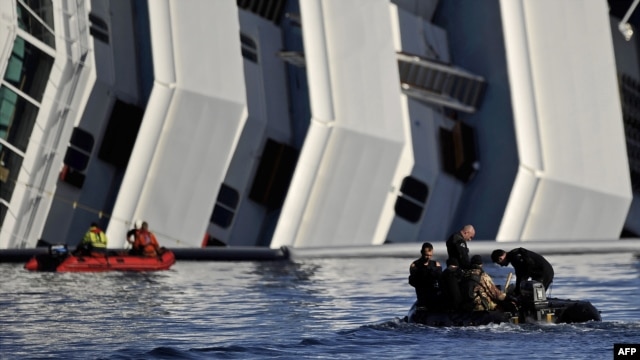 Rescuers pass in a small boat near the stricken cruise liner "Costa Concordia" lying aground in front of Giglio Island off the coast of Italy. 