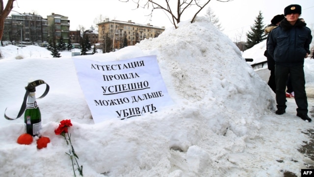 A policeman stands near a poster, flowers, and a champagne bottle left by protesters during their rally against police abuse outside the local Interior Ministry headquarters in Kazan in March.