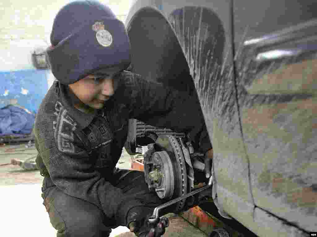 A 12-year-old boy works in a garage in Baghdad.