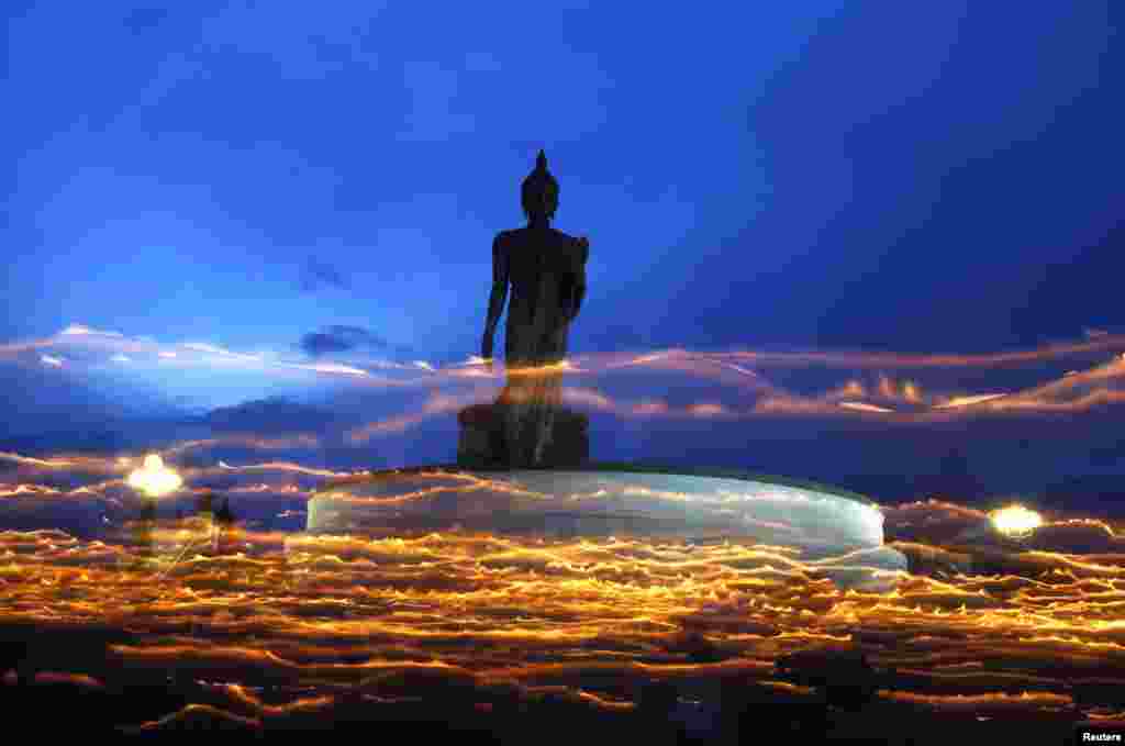 Thai Buddhists carry candles while encircling a large Buddha statue during Vesak Day, an annual celebration of Buddha's birth, enlightenment and death, at a temple in Nakhon Pathom Province on May 24. (Reuters/Chaiwat Subprasom)