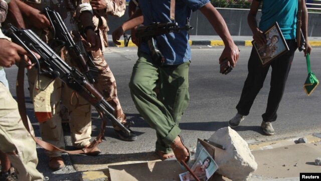 Libyan rebel fighters step on a picture of Muammar Qaddafi at a checkpoint in Tripoli on August 22.