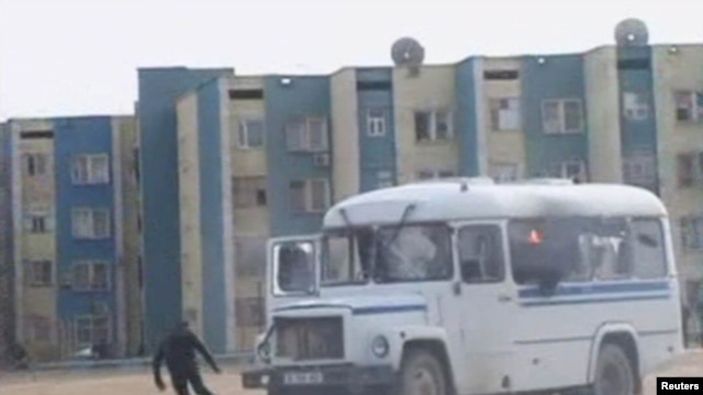 Kazakhstan -- A protester runs from a police vehicle on fire in the Kazakh town of Zhanaozen in this still image taken from video acquired by Reuters TV, 16Dec2011  