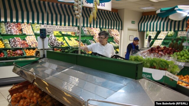 Olga Osypova, a 65-year-old Moscow pensioner, shops in a Moscow market, with empty shelves that would normally hold European vegetables.