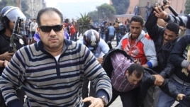 Egypt -- A plainclothes policeman (L) runs to attack a foreign journalist during a demonstration in Cairo, 28 January, 2011
