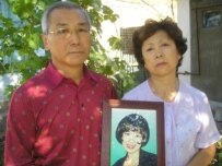 The parents of Zhanetta Tsoi with a picture of her (RFE/RL)