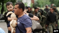 A man carries his son as he leaves his apartment building during an ongoing shoot-out between pro-Russian militants and border guards defending the Federal Border Headquarters in Luhansk on June 2.
