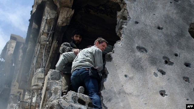 A photograph shortly before he was killed shows Tim Hetherington (center) being assisted by rebels as he climbs down a building after gunshots rang out in the besieged Libyan city of Misurata on April 20.